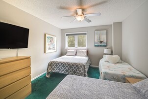 Un dormitorio con ventilador de techo, televisión, ventana y dos camas.