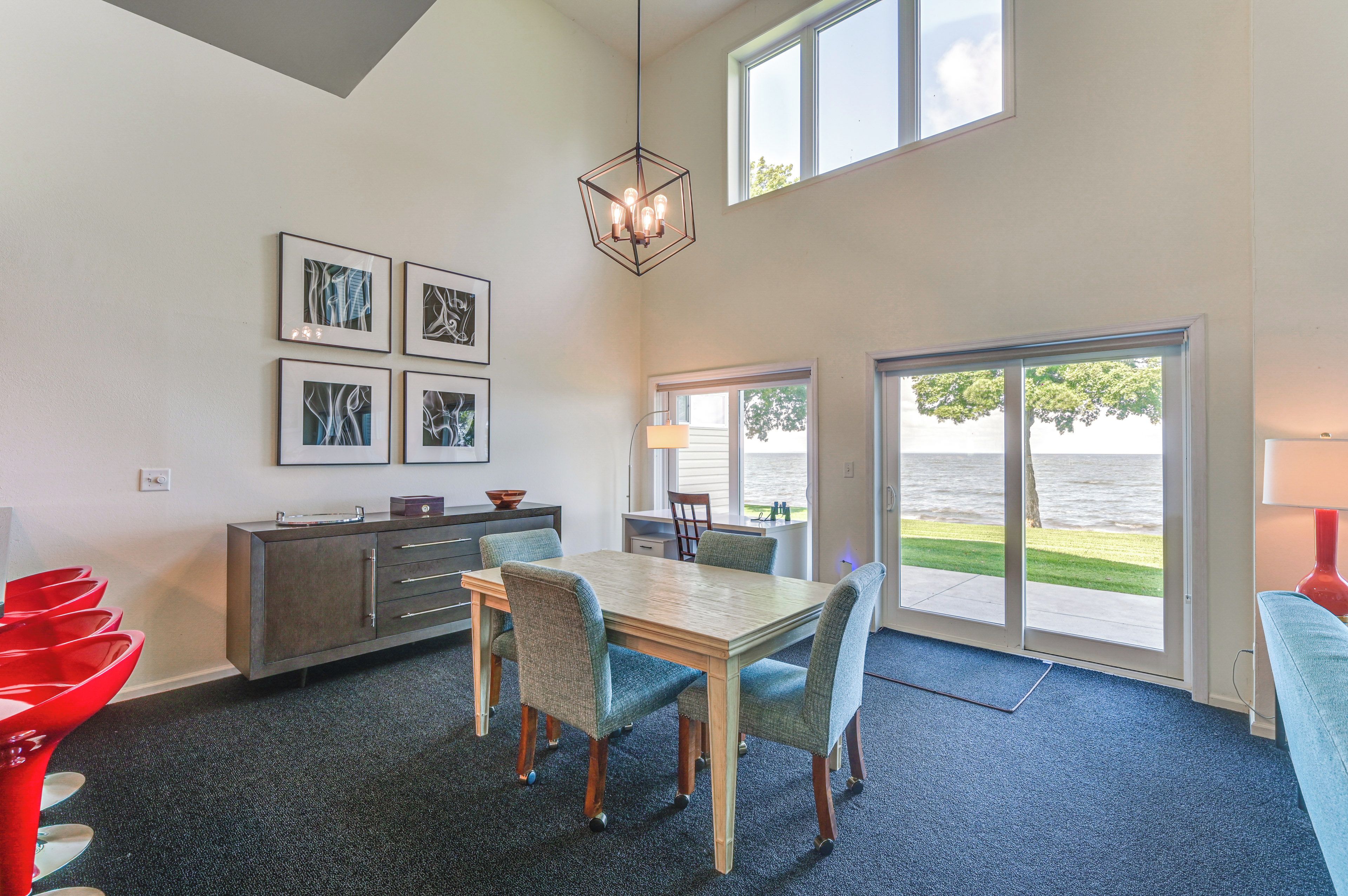 A modern dining area with a table and chairs, a kitchen counter, and a view of the outdoors through large windows.