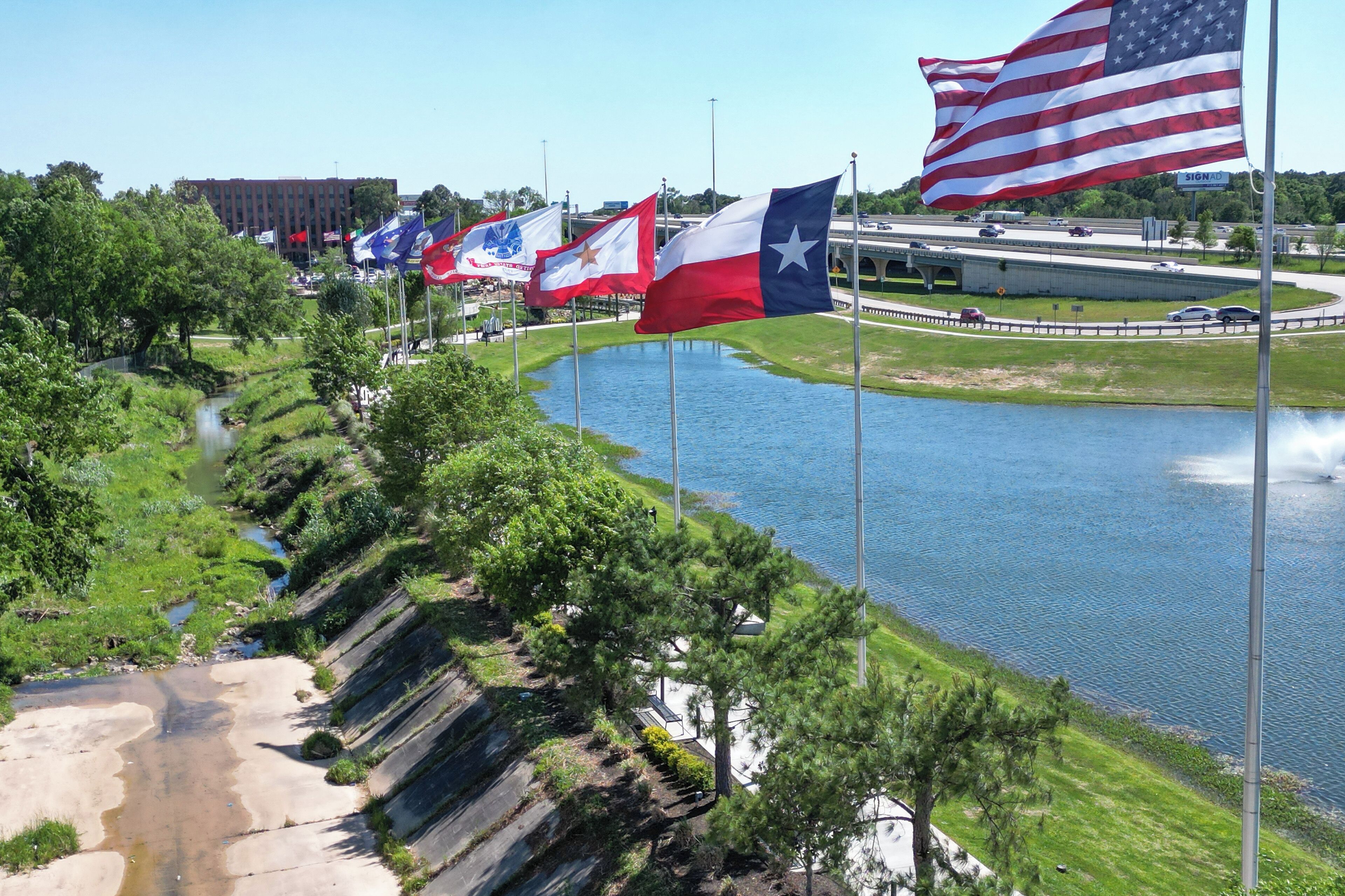 Un río con banderas, un puente y un edificio al fondo.