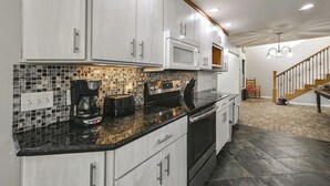 Una cocina moderna con gabinetes blancos, microondas, cafetera y tostadora.
