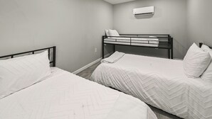 Una habitación con dos literas, un aire acondicionado de pared y una pared lisa.