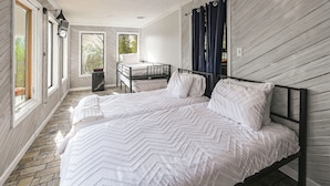 Quarto com cama grande, escrivaninha e janela com cortinas.