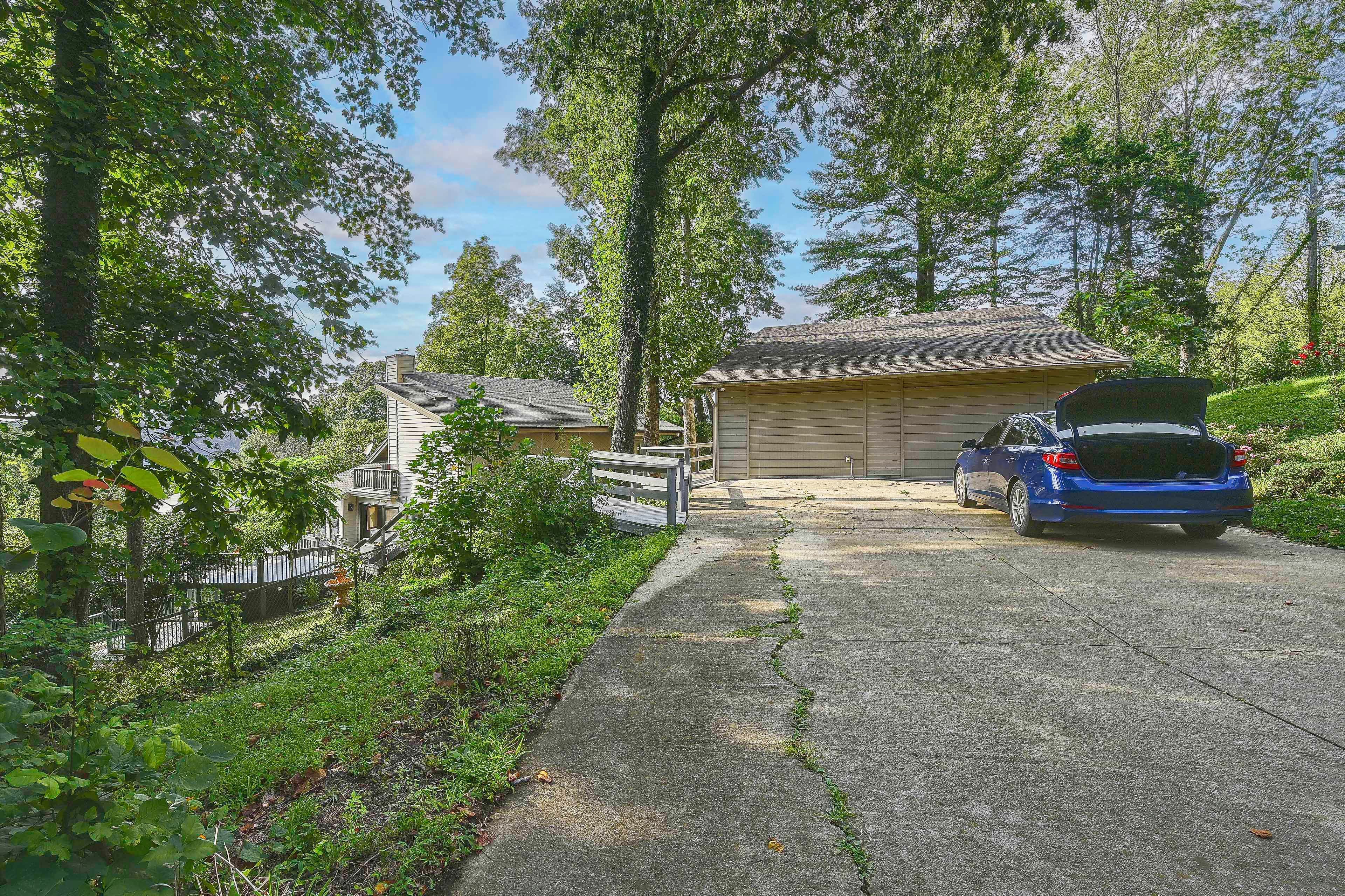 A residential driveway with a garage, a parked car, and a wooden fence.