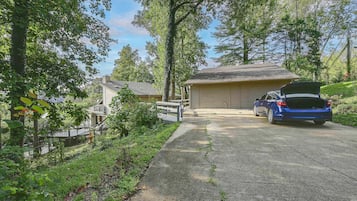 A residential driveway with a garage, a parked car, and a wooden fence.