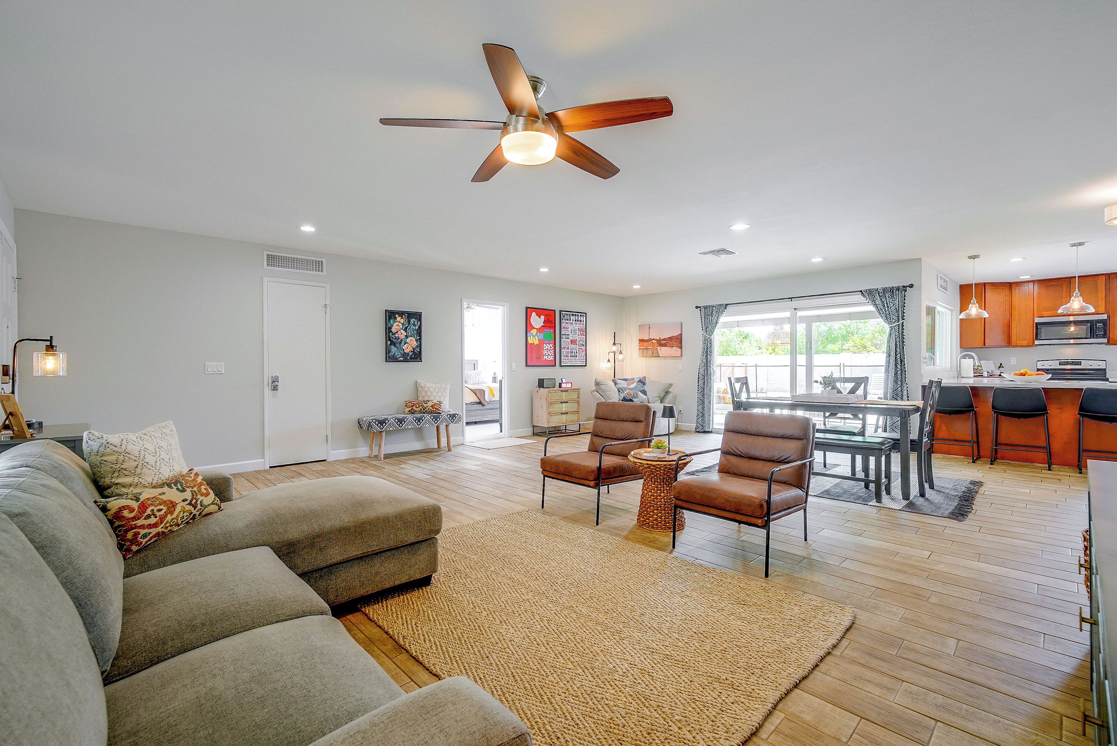 A modern living room with a sofa, chairs, a coffee table, and a ceiling fan.