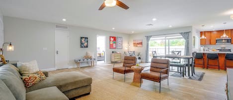 A modern living room with a sofa, chairs, a coffee table, and a ceiling fan.