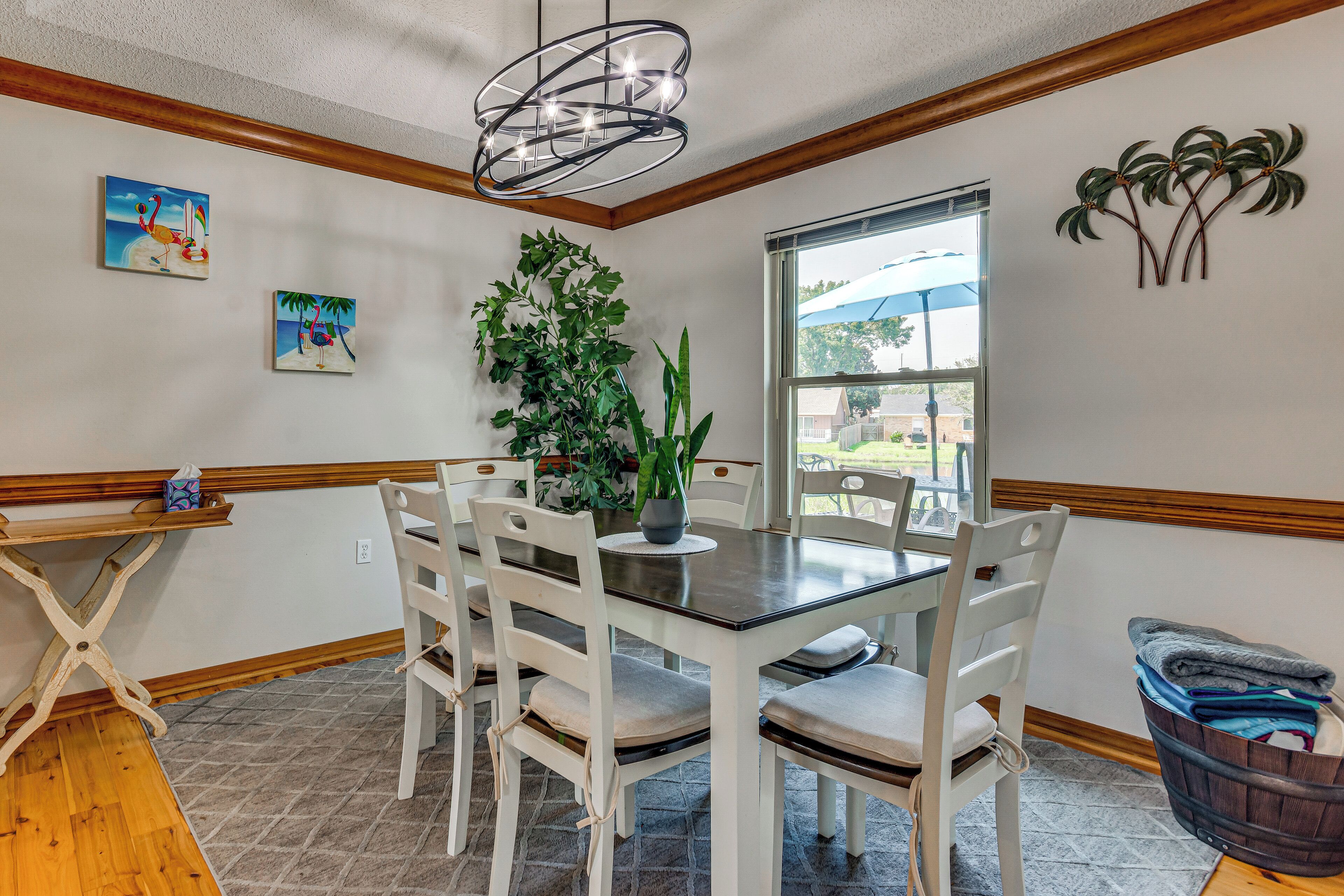 A dining area with a table and chairs, a plant, and artwork on the walls.