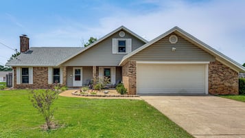 A two-story house with a garage, a brick chimney, and a well-maintained lawn.