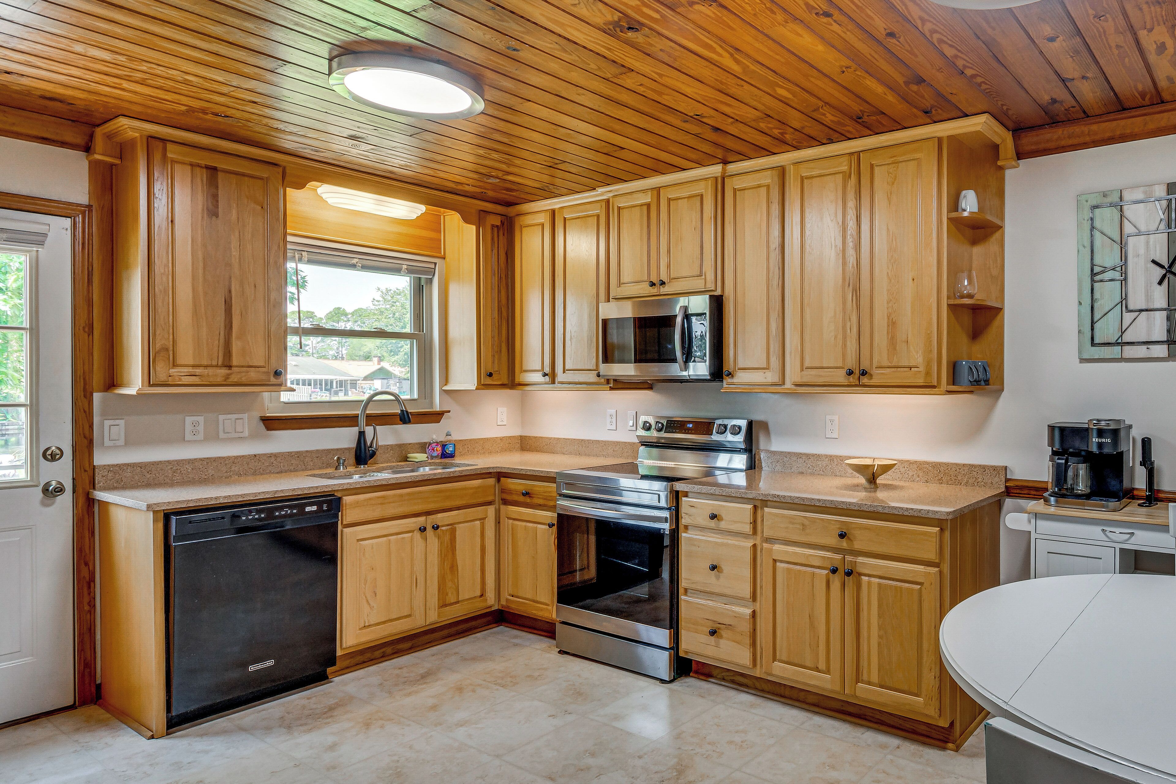 A kitchen with wooden cabinets, a dishwasher, a microwave, an oven, and a coffee maker.