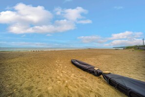 A sandy beach with a black bag and a stone on it, and a clear sky with clouds. - Family Fun! Indoor Jungle Gym, Hot Tub & Beach (Erie)