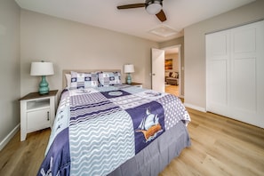 A bedroom with a bed, nightstands, a ceiling fan, and a door leading to another room. - Family Fun! Indoor Jungle Gym, Hot Tub & Beach (Erie)
