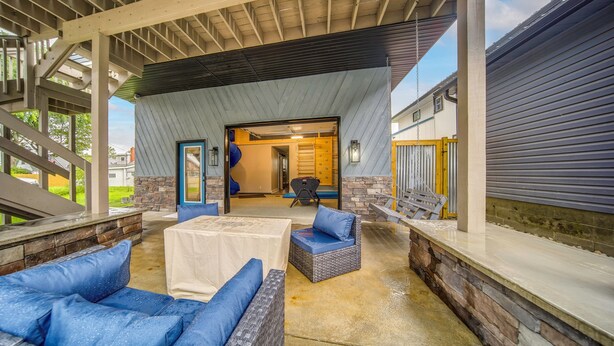 An outdoor covered patio area with seating and a view into the house. - Family Fun! Indoor Jungle Gym, Hot Tub & Beach (Erie)