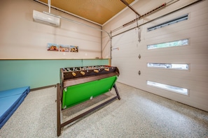 A room with a green futsal table, a blue sofa, and a white door with multiple windows. - Family Fun! Indoor Jungle Gym, Hot Tub & Beach (Erie)