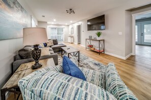 A modern living room with a sofa, a coffee table, and a TV mounted on the wall. - Family Fun! Indoor Jungle Gym, Hot Tub & Beach (Erie)