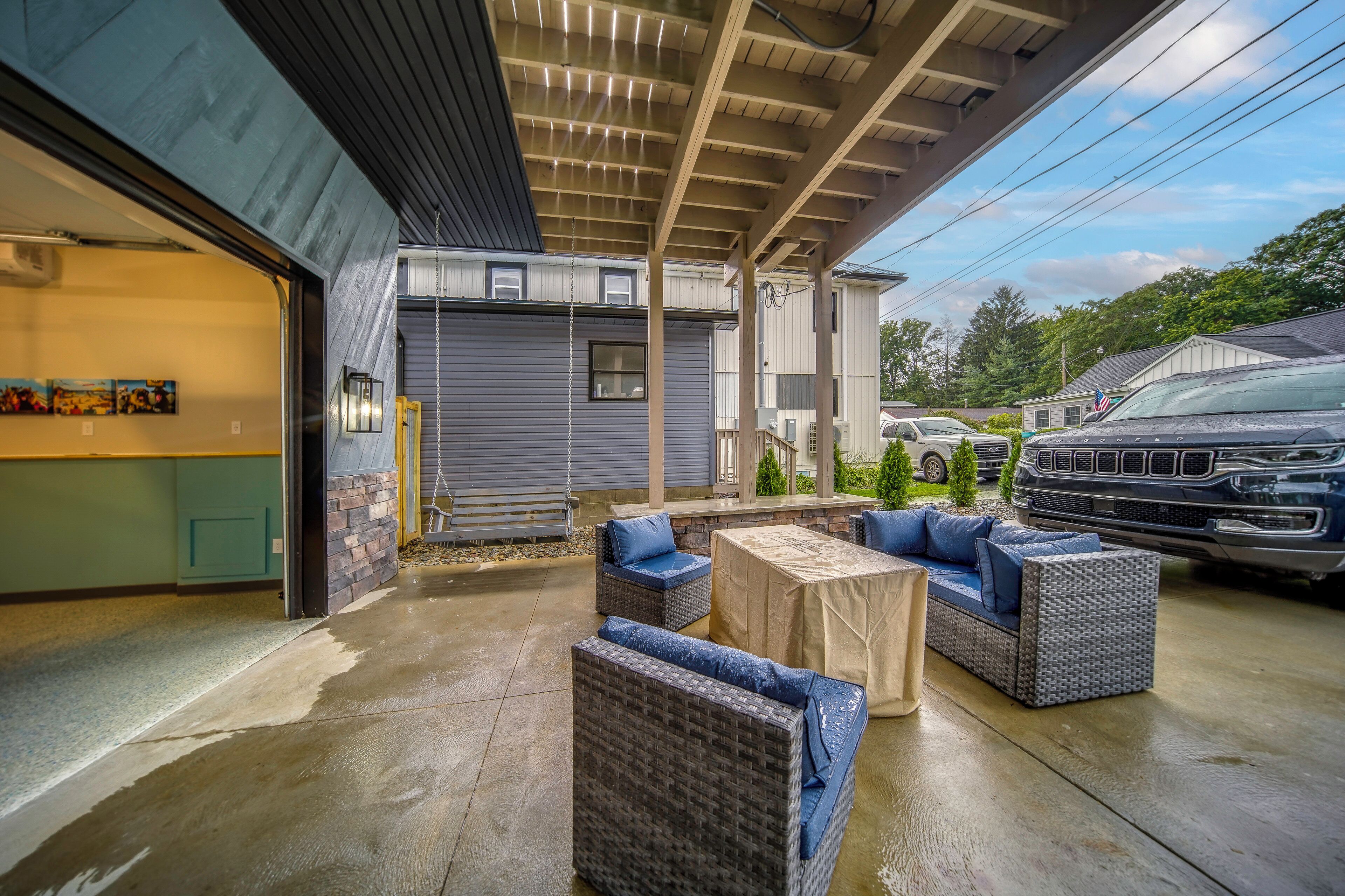 A covered outdoor seating area with wicker furniture and a concrete floor.
