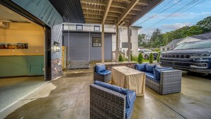 A covered outdoor seating area with wicker furniture and a concrete floor. - Family Fun! Indoor Jungle Gym, Hot Tub & Beach (Erie)