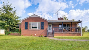 A two-story brick house with a covered porch and a satellite dish. - Quiet Stuart Retreat w/ Yard & Fireplace (Patrick Springs)
