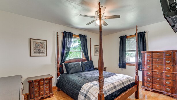 A four-poster bed with a wooden finish, a ceiling fan, and a dresser with multiple drawers. - Quiet Stuart Retreat w/ Yard & Fireplace (Patrick Springs)
