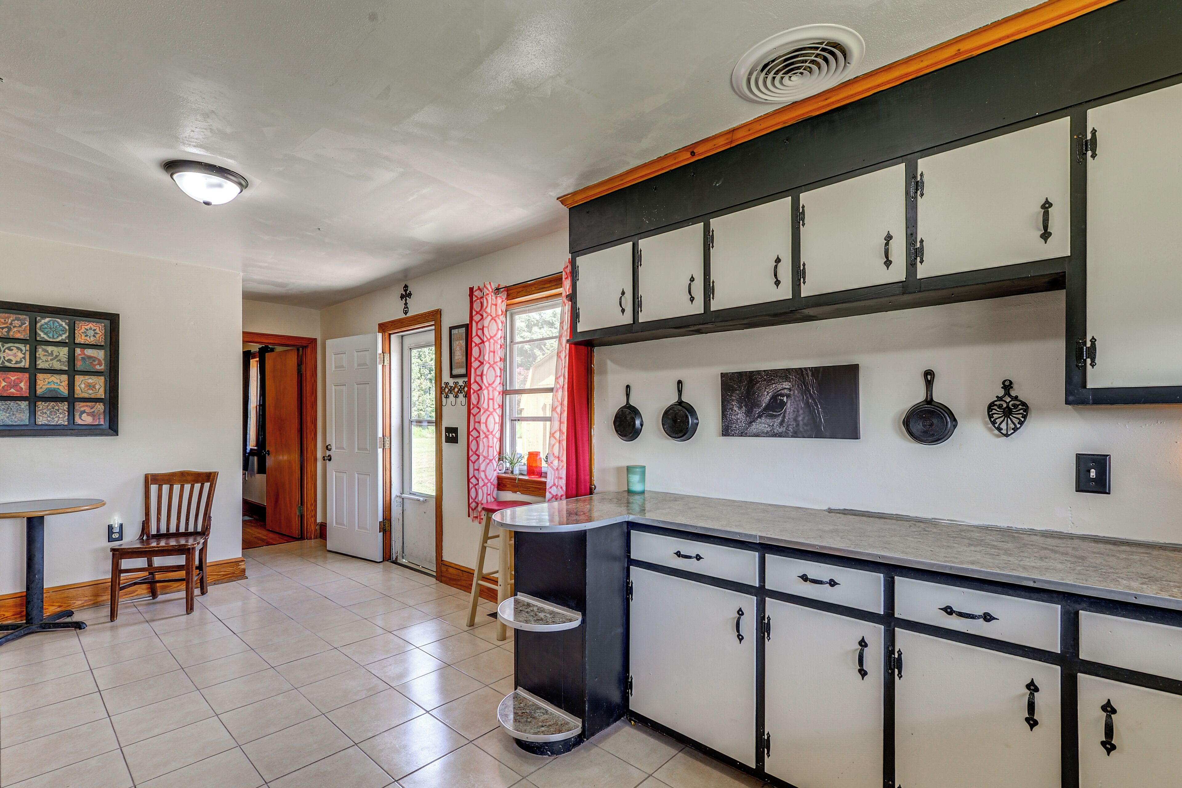 A kitchen with a central island, cabinets, and a dining area with a chair and table.