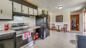 A kitchen with stainless steel appliances, a wooden cabinet, and a tiled floor. - Quiet Stuart Retreat w/ Yard & Fireplace (Patrick Springs)