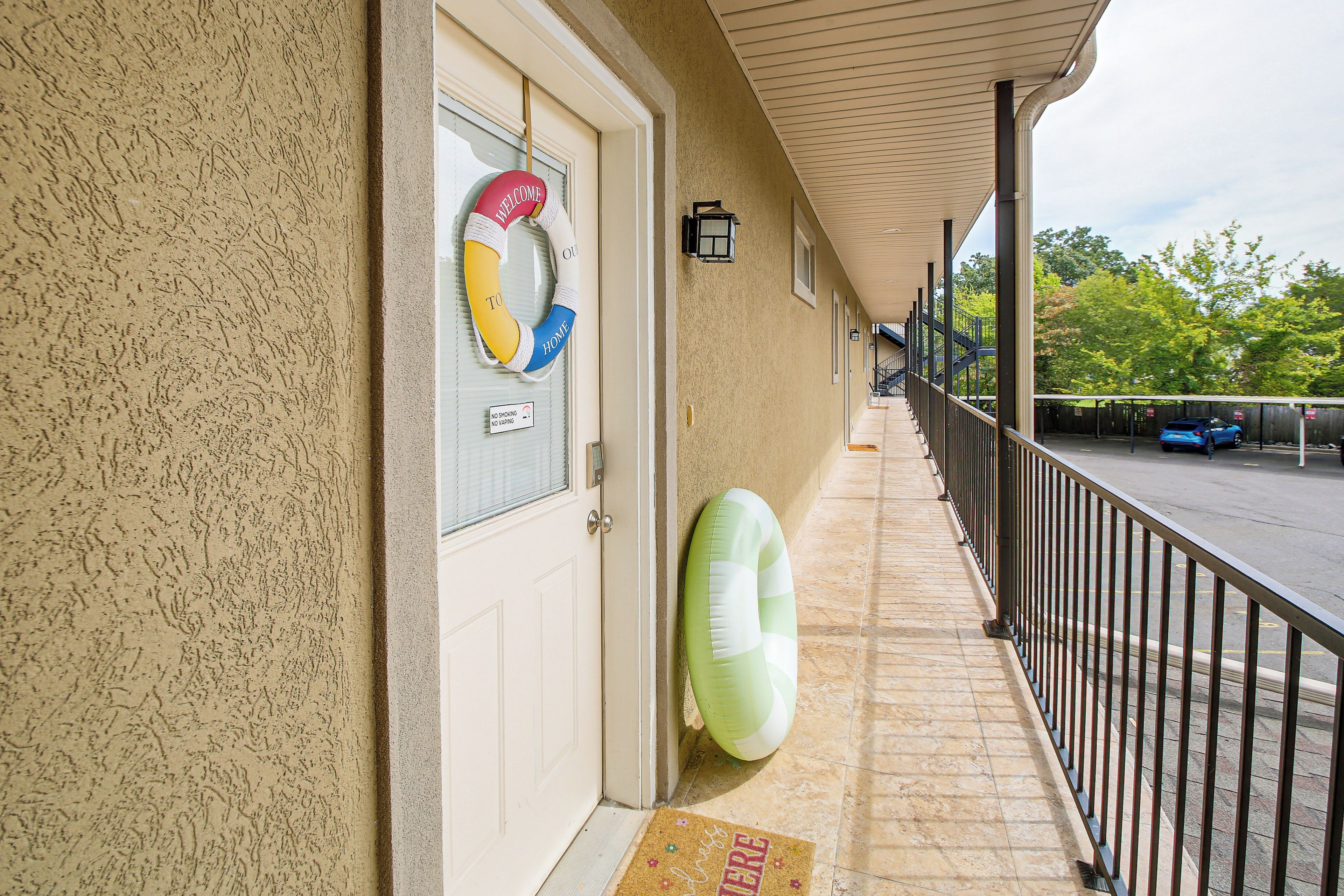A hotel entrance with a welcome sign, a no smoking sign, and a doormat.