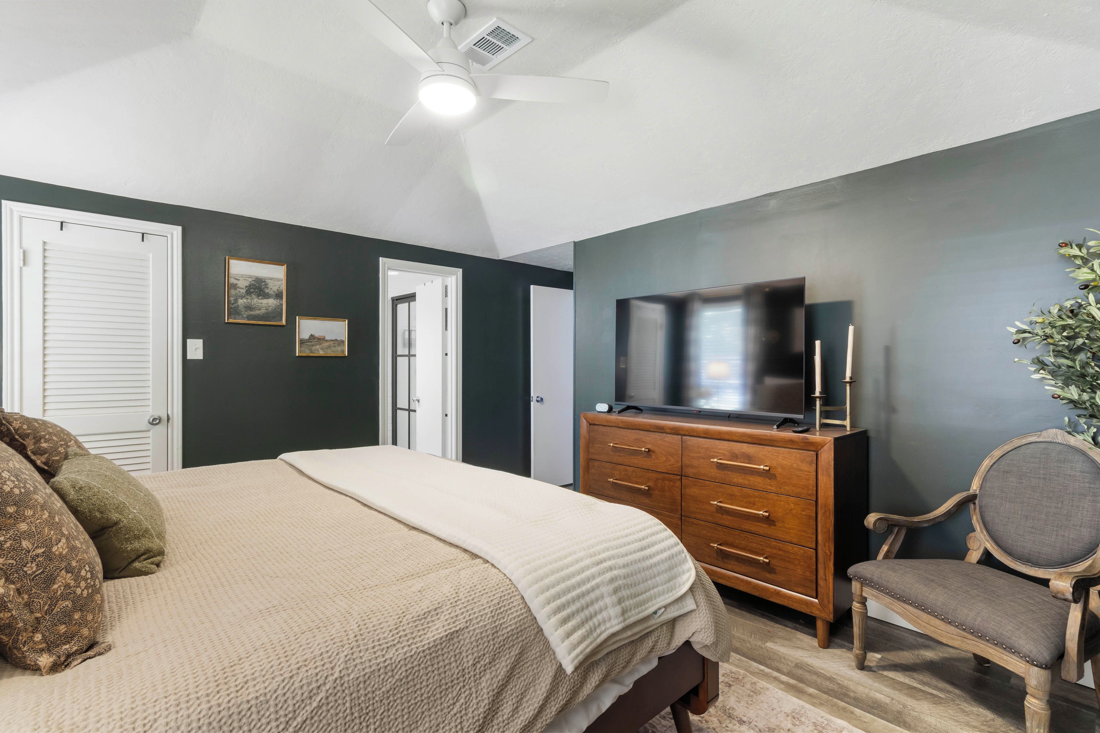 Une chambre à coucher avec un lit, une commode, un téléviseur et une chaise.