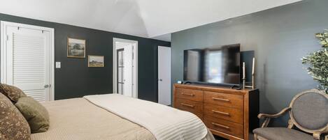 Une chambre à coucher avec un lit, une commode, un téléviseur et une chaise.