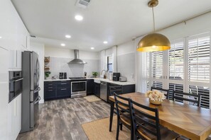 Eine moderne Küche mit Kochinsel, integrierten Geräten und einem Essbereich mit Holztisch und Stühlen.