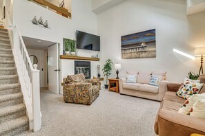 Ein geräumiges Wohnzimmer mit Treppe, Flachbildfernseher, Kamin und einem Gemälde an der Wand.