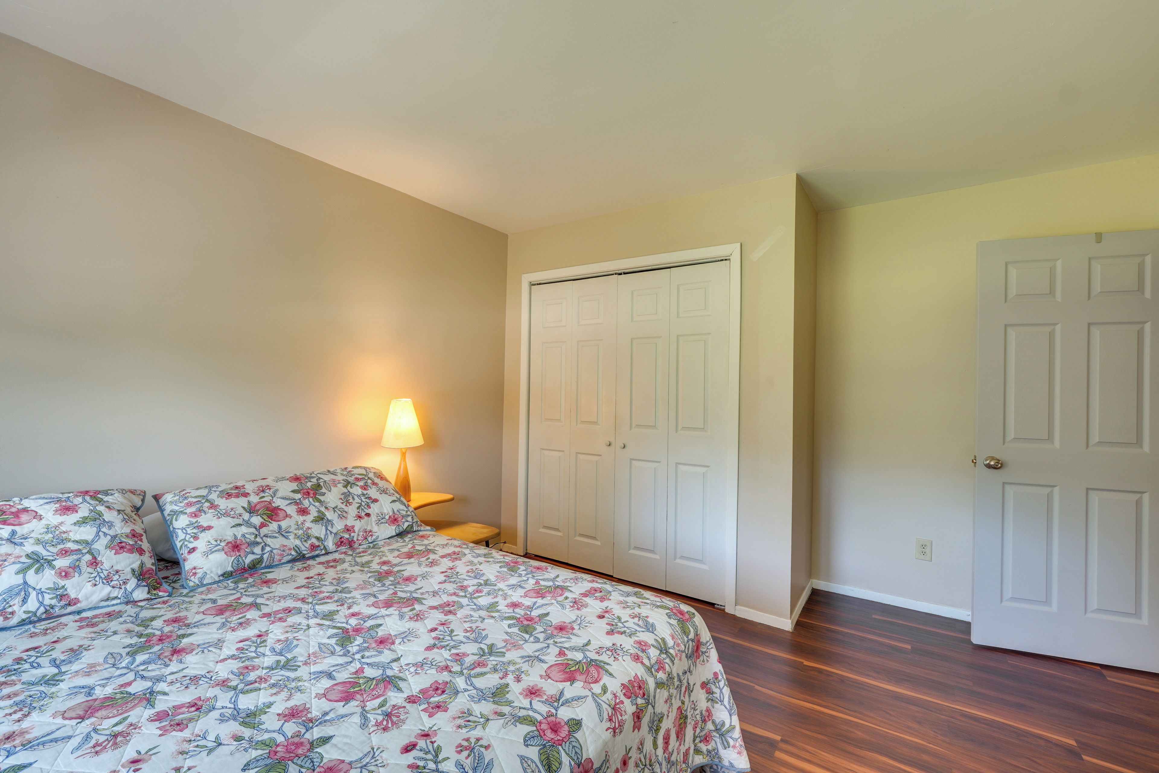 A bedroom with a bed, a nightstand, a lamp, and a closet.