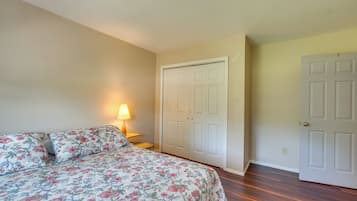 A bedroom with a bed, a nightstand, a lamp, and a closet.