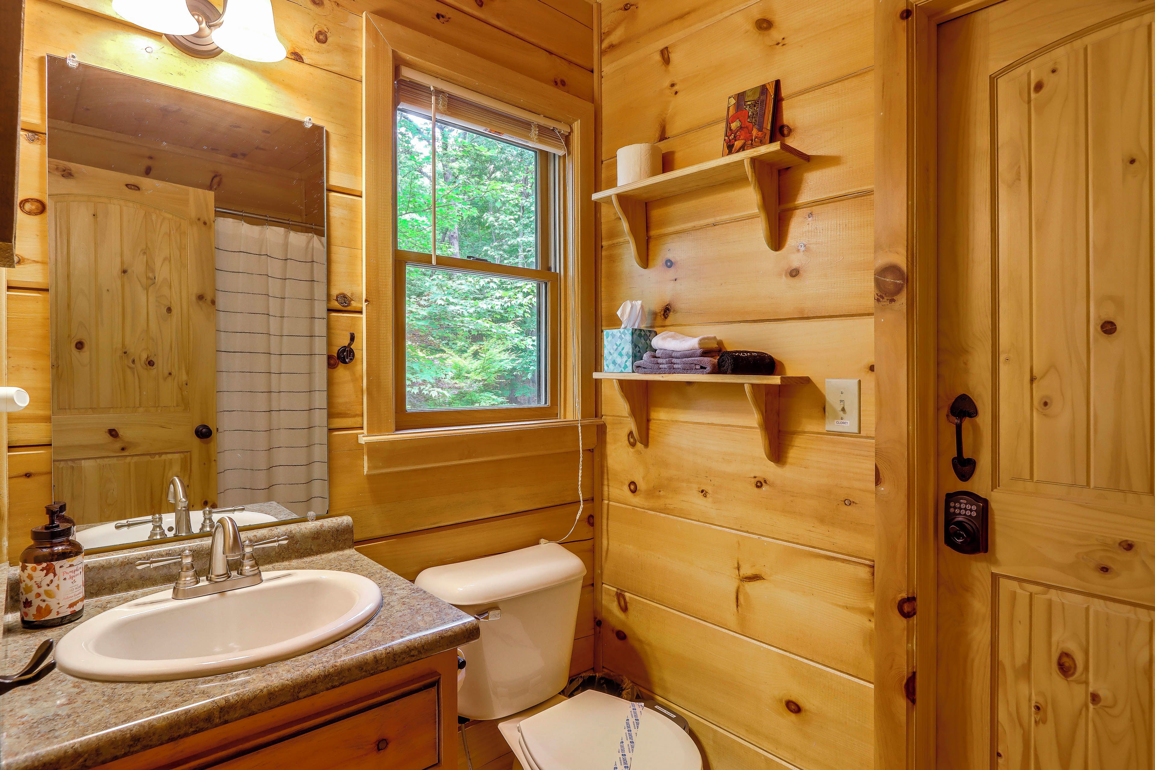 A wooden cabin bathroom with a sink, toilet, and a window.