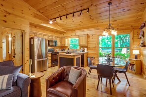 A wooden cabin interior with a kitchen, dining area, and seating. - Private Hot Tub & Deck! Cherry Log Gem (Blue Ridge)