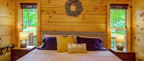 Ein Schlafzimmer einer Holzhütte mit Bett, Kissen, Nachttischen und einem Kranz an der Wand.