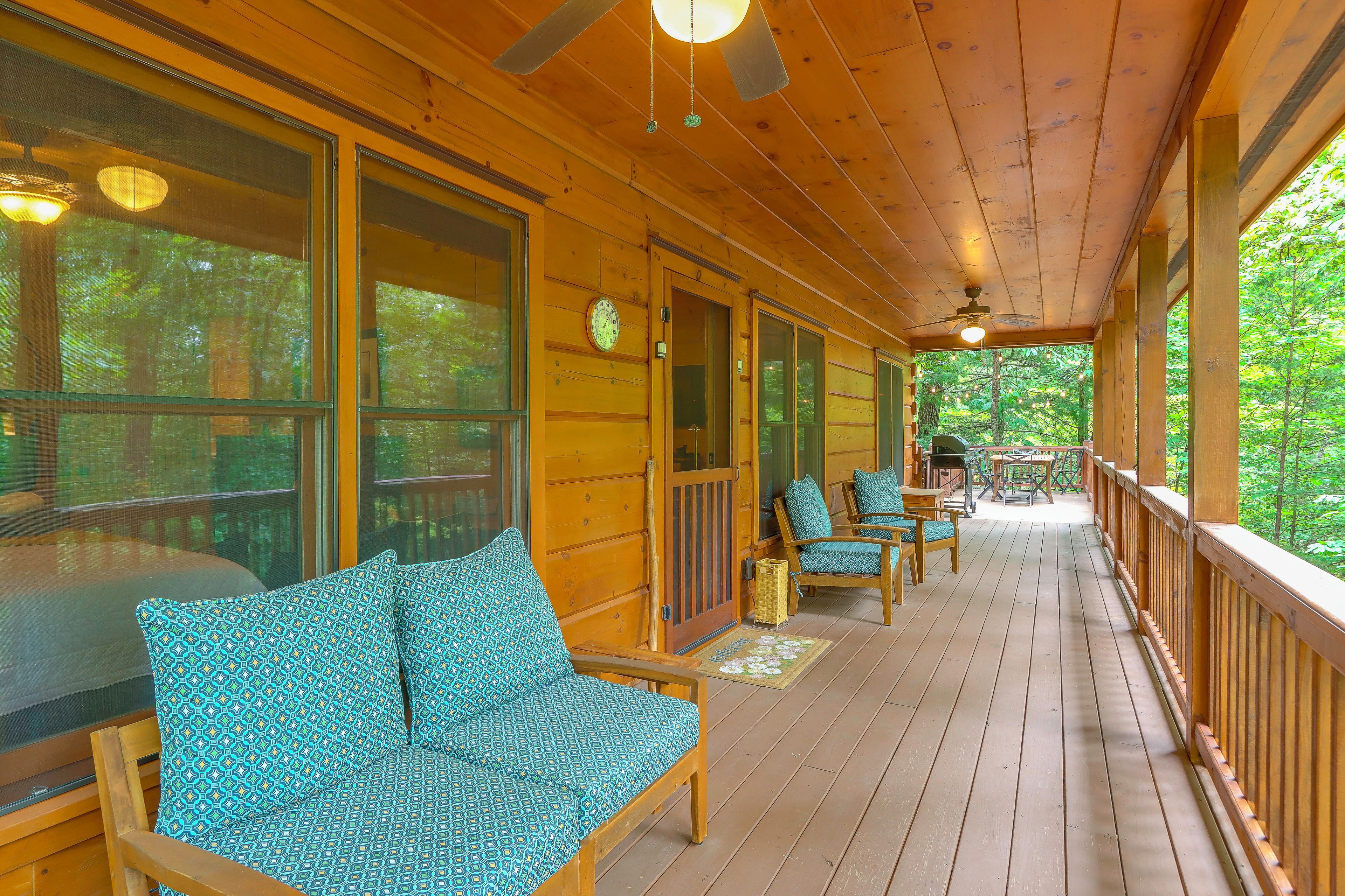 A wooden deck with outdoor seating and a view of the forest.