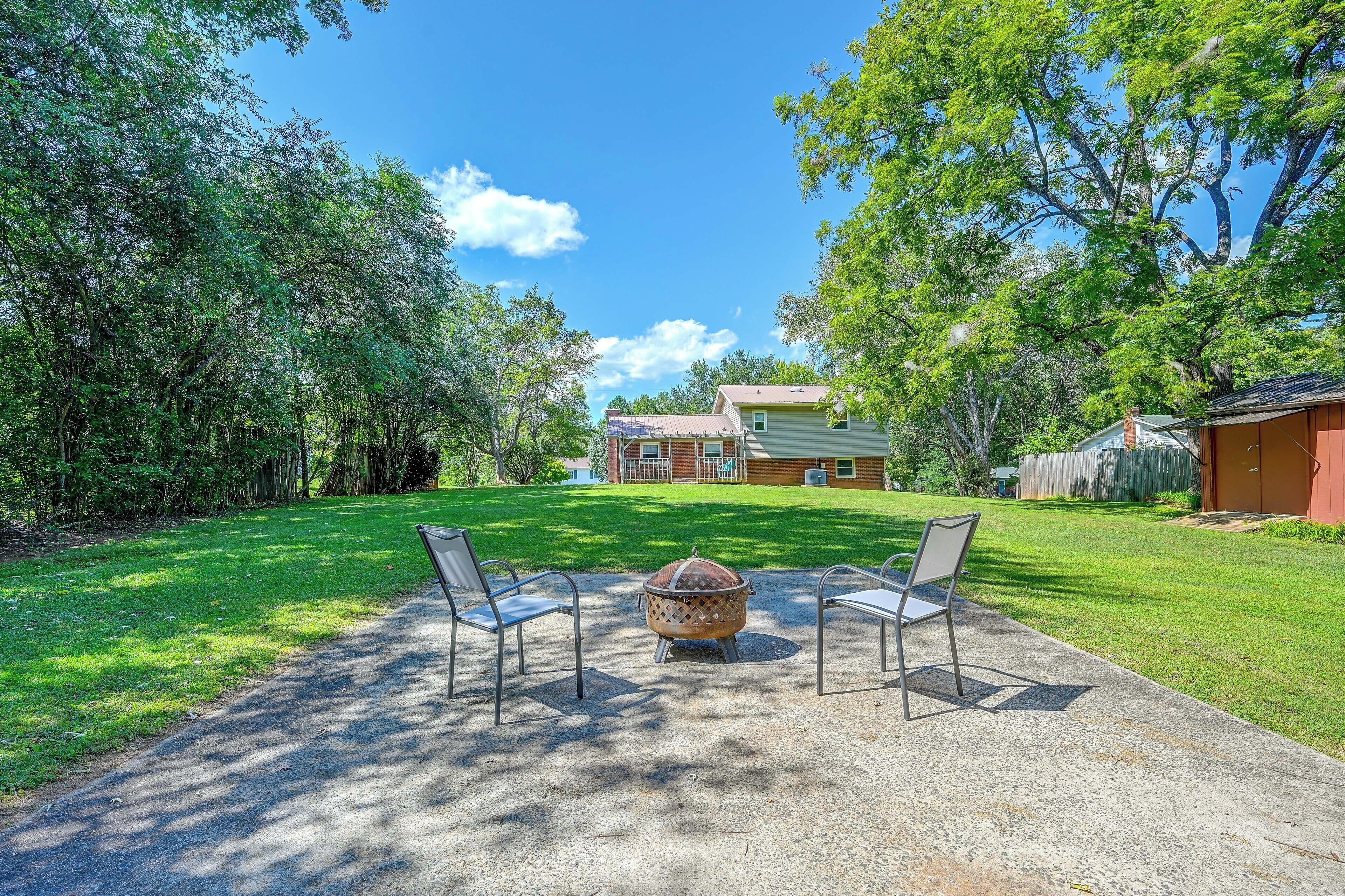 A backyard with a fire pit, two chairs, and a house in the background.