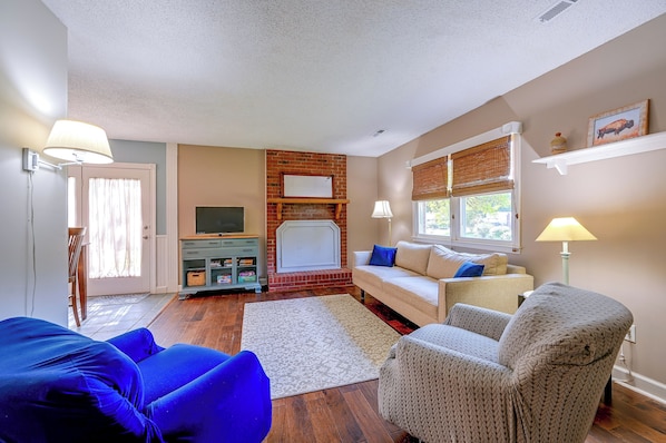 A living room with a fireplace, a sofa, a TV, and a window with blinds. - King Fall Getaway: Fire Pit & Near Pilot Mountain (King)