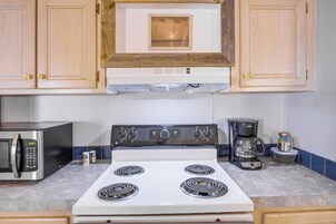 Una cocina con estufa blanca, microondas y cafetera.