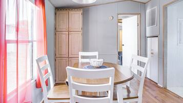 A dining area with a round table, white chairs, and a wooden cabinet.
