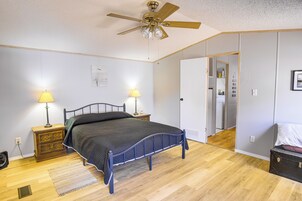 A bedroom with a bed, two bedside lamps, a ceiling fan, and a wooden floor.