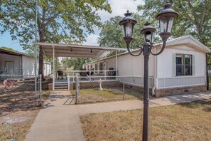 A covered outdoor area with a walkway leading to a building, a lamp post, and a fence.