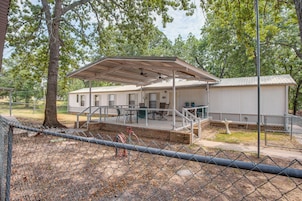 A covered outdoor seating area with tables and chairs, a fenced playground, and a building with a metal roof.
