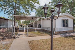 A covered outdoor area with a walkway leading to a building, a lamp post, and a fence.