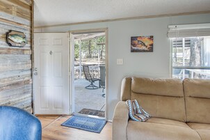 A living room with a beige sofa, a blue rug, and a door leading to an outdoor patio with a table and chairs.
