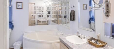 A bathroom with a large bathtub, two sinks, and a mirror.