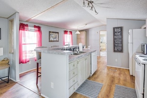 A kitchen with a central island, white cabinets, a refrigerator, and a chalkboard with inspirational quotes.