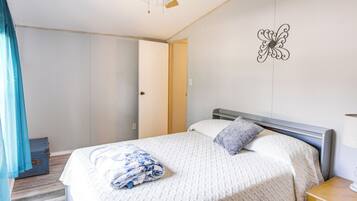A bedroom with a bed, a nightstand, a wall decoration, and a ceiling fan.