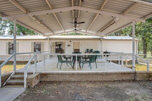 Un espacio de patio cubierto con mesa y sillas, una parrilla de barbacoa y una puerta que da a un edificio.