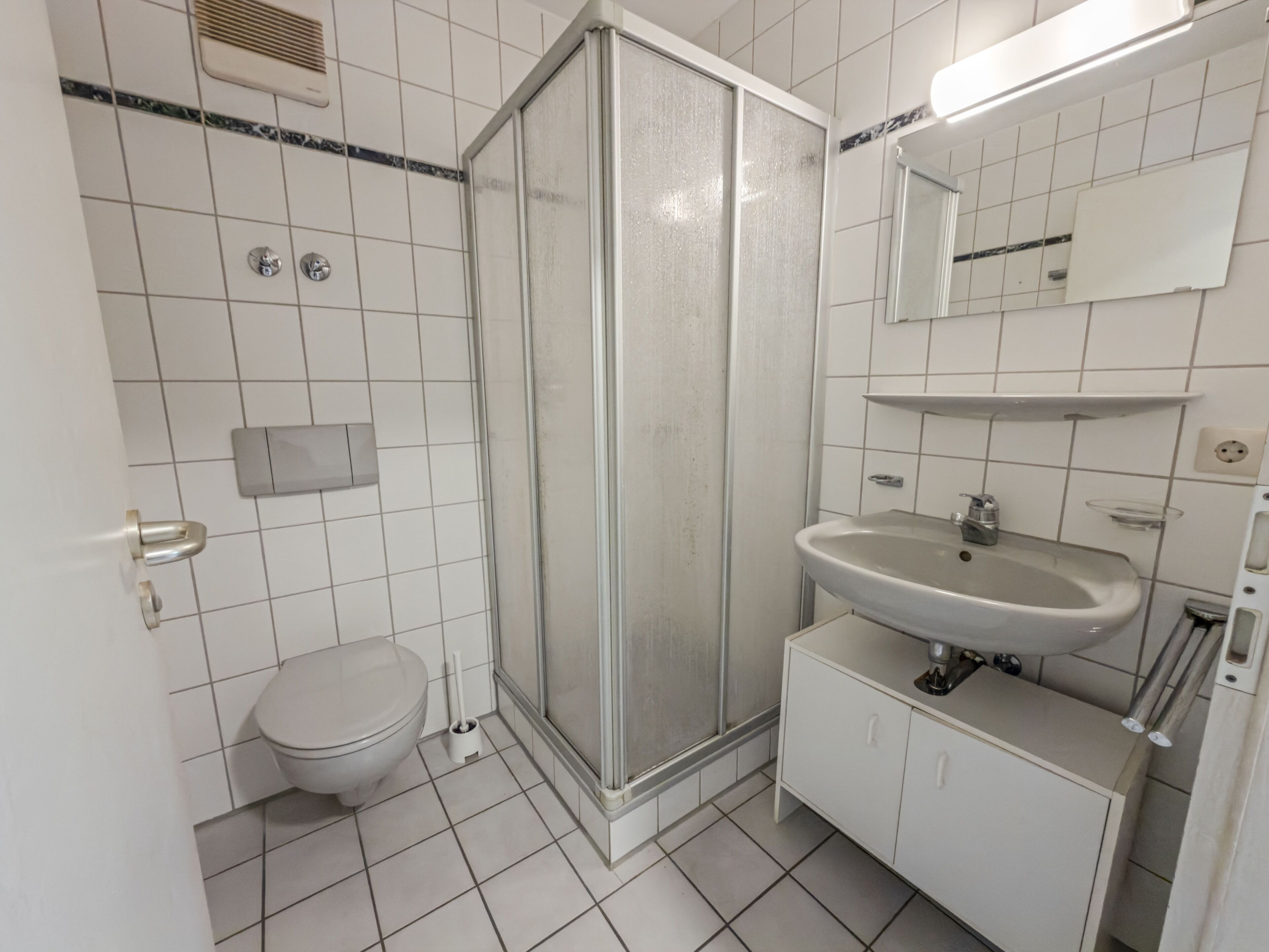 A bathroom with a toilet, a shower enclosure, a sink, and a mirror.
