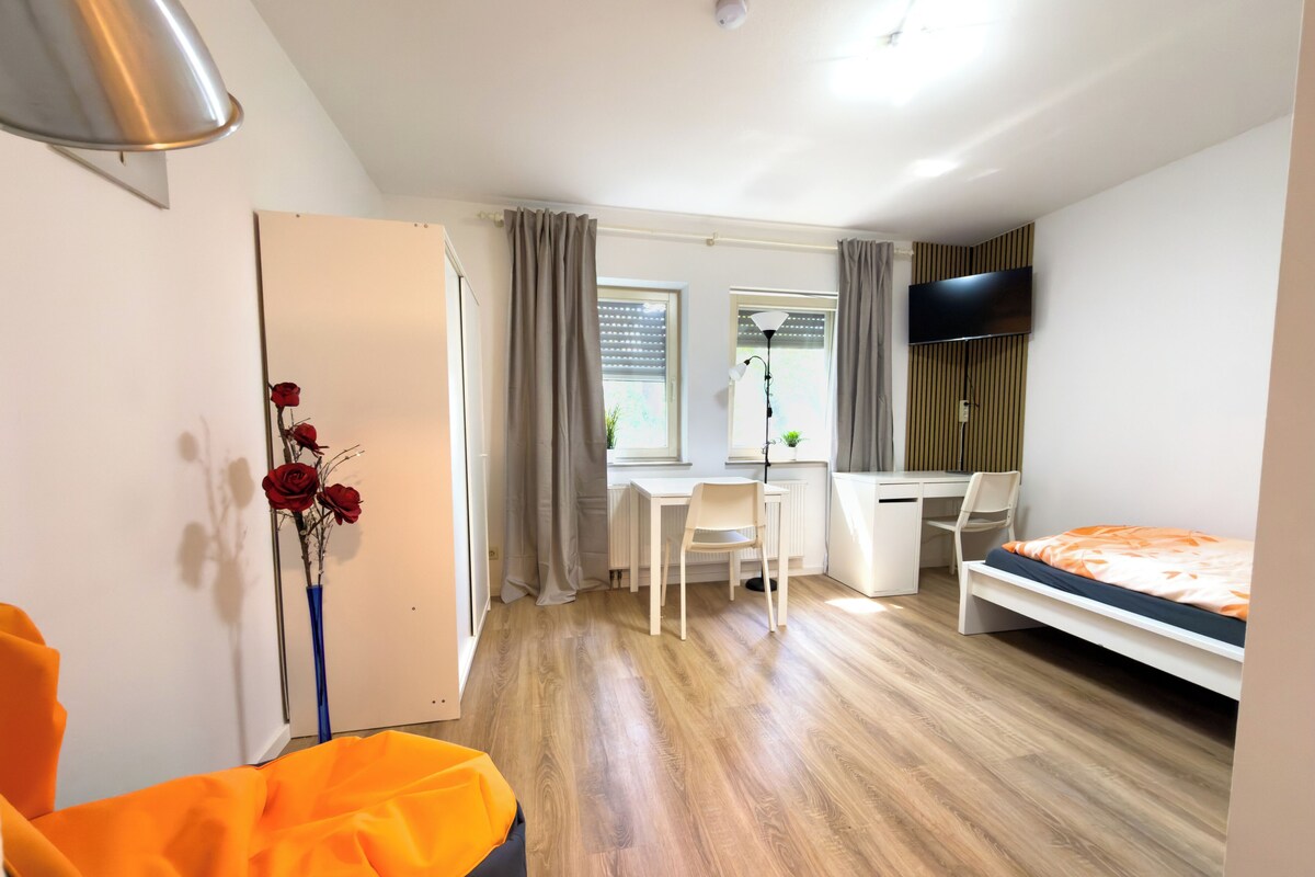 A compact room with a bed, a desk, a chair, and a radiator.